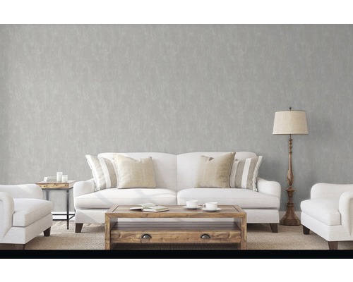 Wohnzimmer mit Sofa, Sessel, Tisch und Stehlampe vor einer grauen Wand