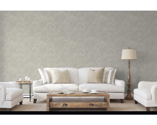 Wohnzimmer mit Sofa, Sessel, Tisch und Stehlampe vor einer gemusterten Wand