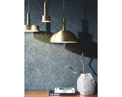 Drei goldfarbene Pendelleuchten vor einer Wand mit Zickzackmuster