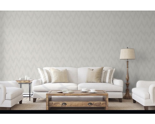 Wohnzimmer mit Tapete im Zickzackmuster, Sofa, Sessel, Tisch und Stehlampe für eine helle und einladende Atmosphäre.