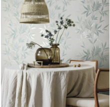 Esstisch mit Tischdecke, Vasen und Blumendekoration vor einer floral gemusterten Tapete