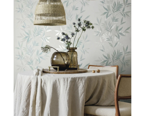 Esstisch mit Tischdecke, Vasen und Blumendekoration vor einer floral gemusterten Tapete