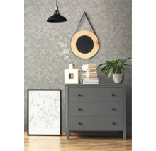 Dekoratives Interieur mit gemusterter Tapete, Kommode, Spiegel, Lampe und Zimmerpflanze