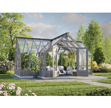 Gewächshaus mit Glaswänden und Doppeltür in einem Garten mit Pflanzen und Rasen.