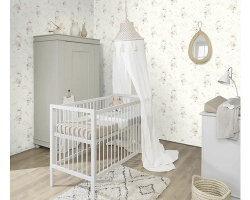 Helles Kinderzimmer mit Gitterbett, Kleiderschrank, Wickelkommode und Tapete mit Hasenmotiven