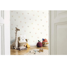 Kinderzimmer mit Herzmuster-Tapete, Giraffenkuscheltier und dekorativen Kissen