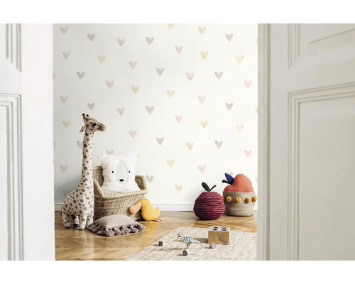 Kinderzimmer mit Herzmuster-Tapete, Giraffenkuscheltier und dekorativen Kissen