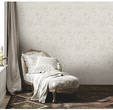 Szene mit beiger floral gemusterter Tapete, Liege mit Kissen und Decke sowie Vorhang