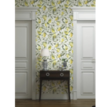 Raumansicht mit Tapete mit Zitronen- und Olivenmuster, Kommode, Lampe und weißen Türen.