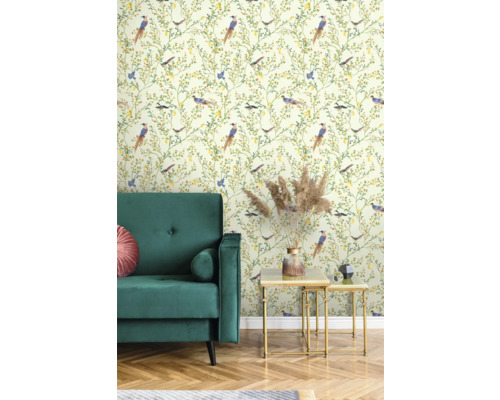 Raumansicht mit grünen Samtsofa, goldenem Satztisch und Tapete mit Vogelmuster