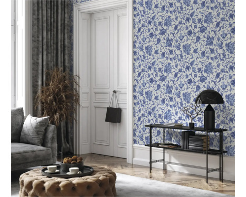 Wohnzimmer mit blumiger Tapete, Couch, Hocker und Dekorationen für ein gemütliches Ambiente