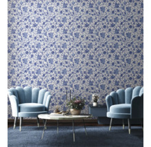 Wohnzimmer mit floral gemusterter Tapete, zwei Sesseln, einem Couchtisch und einem Beistelltisch.