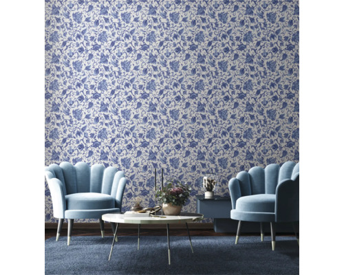 Wohnzimmer mit floral gemusterter Tapete, zwei Sesseln, einem Couchtisch und einem Beistelltisch.