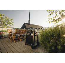 Terrasse mit Grill, Holztisch und Stühlen vor dem Hintergrund einer Kirche