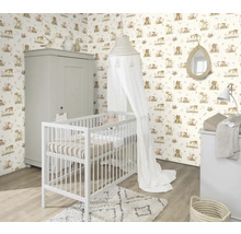 Kinderzimmer mit Gitterbett, Wickelkommode und Schrank vor einer Tapete mit Tiermotiven.