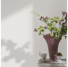 Dekorative Blumenvase mit Blumen, Kaffeetasse und Gebäck auf einem Beistelltisch