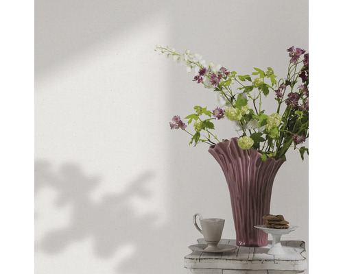 Dekorative Blumenvase mit Blumen, Kaffeetasse und Gebäck auf einem Beistelltisch