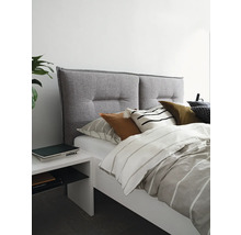 Bett mit grauem Stoffkopfteil und weißem Nachttisch