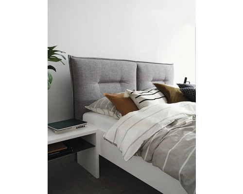 Bett mit grauem Stoffkopfteil und weißem Nachttisch