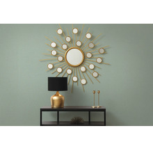 Dekoratives Interieur mit Spiegel in Sonnenform, Lampe und Kerzenständern auf einem Regal.