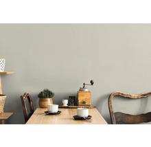 Ein heller Raum mit einem Holztisch, zwei Stühlen, Tassen und Dekorationen an der Wand