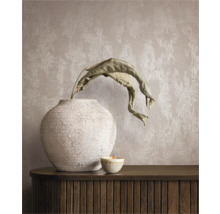Dekoratives Stillleben mit Vase, Pflanze und Kerze auf einem Sideboard vor einer Wandtapete.