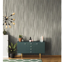 Wohnzimmer mit grauer Wandverkleidung in Wellenoptik, Sideboard und Lampe