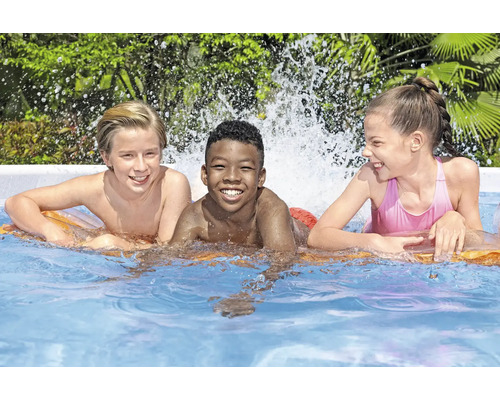 Drei Kinder lachen im Schwimmbecken auf einer Luftmatratze.