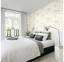 Schlafzimmer mit floraler Tapete, Bett und Fenstertüren zum Balkon.