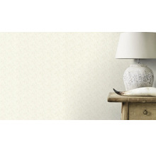 Nahaufnahme einer Wand mit einer Tapete mit floralem Muster, neben der eine Lampe auf einem Holztisch steht