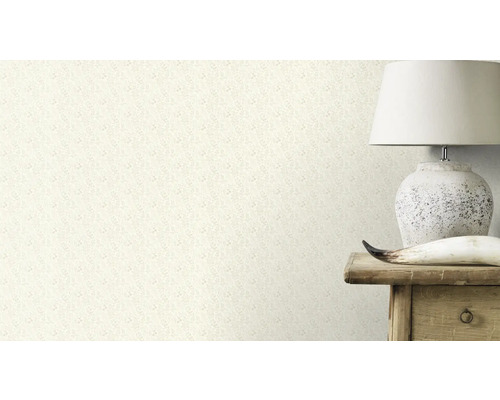 Nahaufnahme einer Wand mit einer Tapete mit floralem Muster, neben der eine Lampe auf einem Holztisch steht