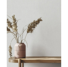 Dekorative Tapete mit Textilmuster und Vase mit Ziergras auf einem Holztisch