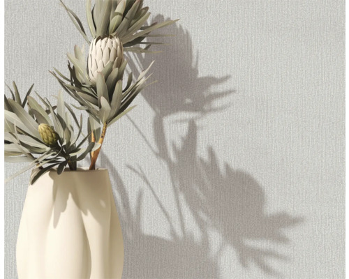 Dekorative Vase mit Protea-Blüten vor einer strukturierten Wand