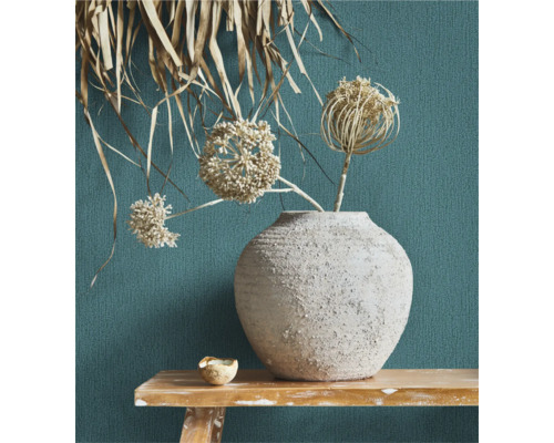 Dekorative Blumenvase mit Trockenblumen auf einem Holztisch vor einer strukturierten Wand