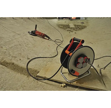 Verlängerungskabeltrommel mit Kabel und Winkelschleifer auf einer Baustelle