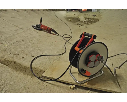 Verlängerungskabeltrommel mit Kabel und Winkelschleifer auf einer Baustelle