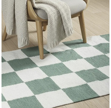 Dekorative Bodenszene mit Teppich im Schachbrettmuster unter einem Stuhl mit Strickdecke.