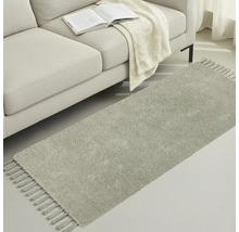 Grauer Teppichläufer mit Fransen neben einem Sofa mit Buch