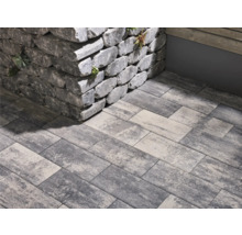 Graue Pflastersteine und eine Mauer aus Steinblöcken im Außenbereich.