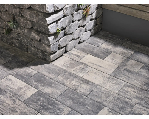 Graue Pflastersteine und eine Mauer aus Steinblöcken im Außenbereich.
