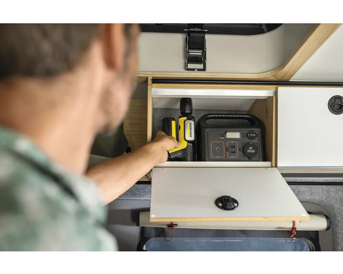 Mann verstaut Kärcher Reinigungsgerät und Powerstation in einem Schrank