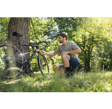 Mann reinigt Fahrrad mit tragbarem Reiniger im Freien