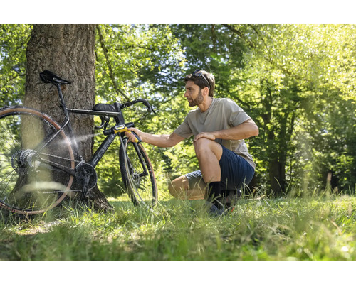 Mann reinigt Fahrrad mit tragbarem Reiniger im Freien