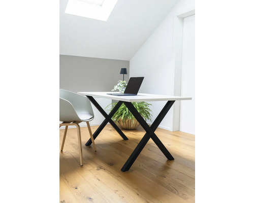 Schreibtisch mit Laptop, Lampe und Pflanze in hellem Raum.