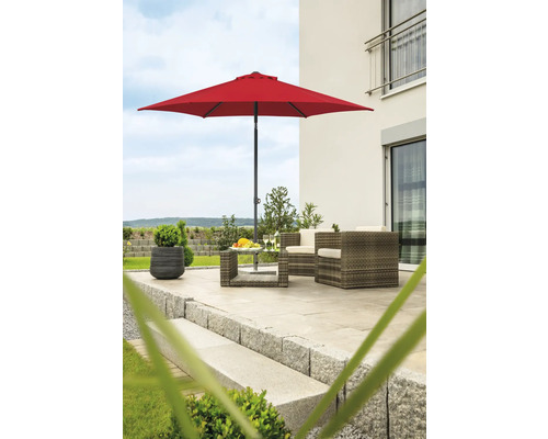 Gartenszene mit rotem Sonnenschirm, Rattanmöbeln und Pflanzkübel auf einer Terrasse