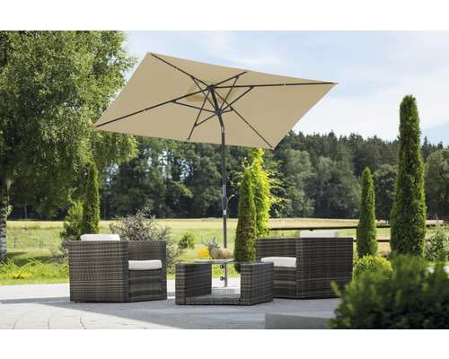 Gartenszene mit Rattanmöbelset, bestehend aus Sesseln, Tisch und einem rechteckigen Sonnenschirm