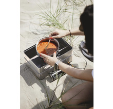 Person kocht Eintopf auf einem Gaskocher im Freien.