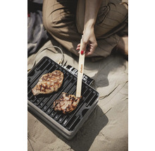 Grillszene mit Person, Grillfleisch und Enders Grillzange auf tragbarem Grill