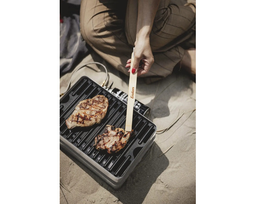 Grillszene mit Person, Grillfleisch und Enders Grillzange auf tragbarem Grill