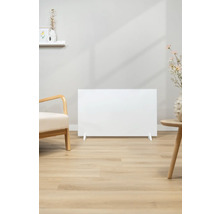 Szene mit einem weißen Heizpaneel auf einem hellen Holzboden, neben einem Sessel und einem Beistelltisch.